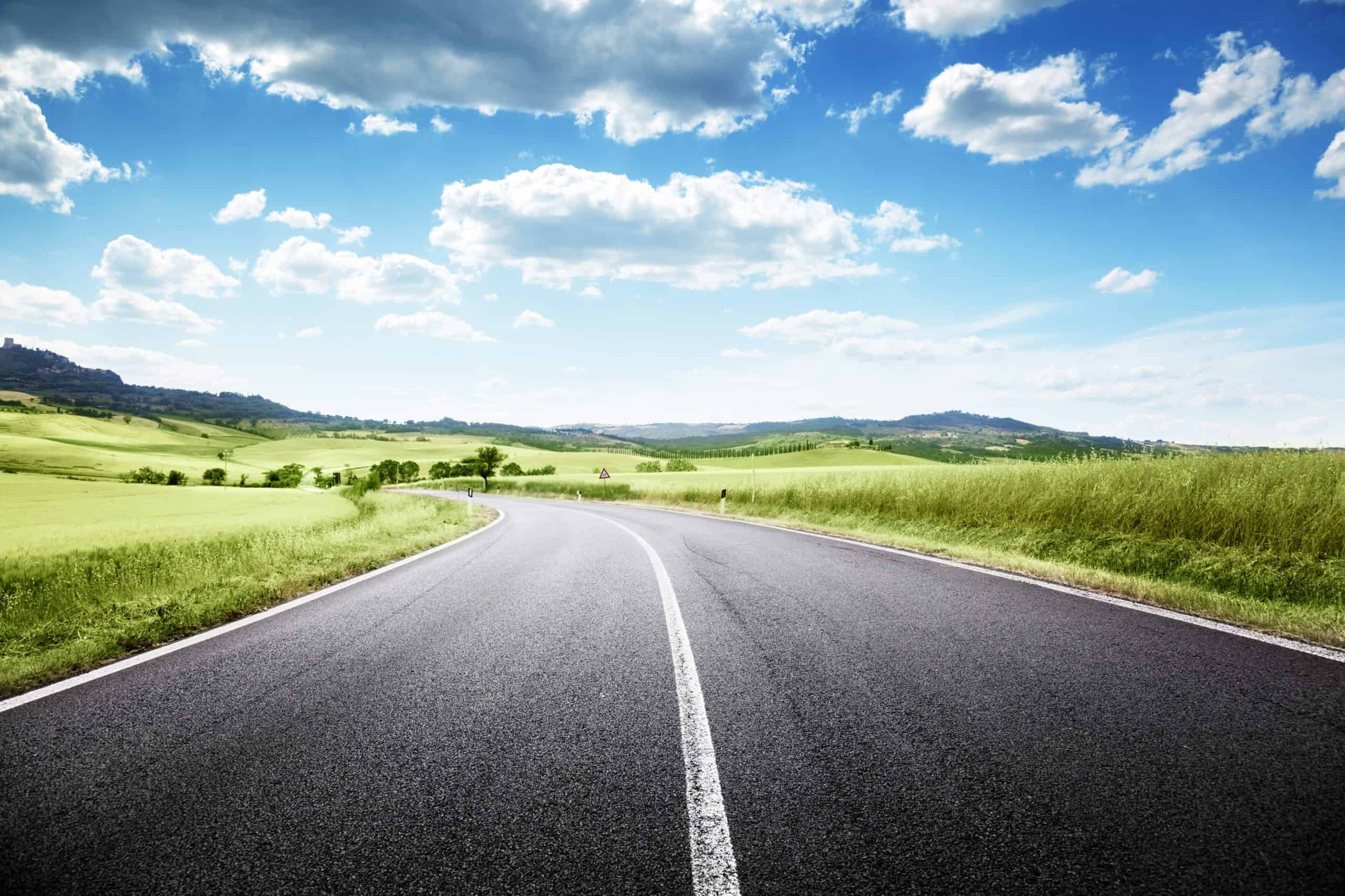 Paved road with grassy side and blue sky above